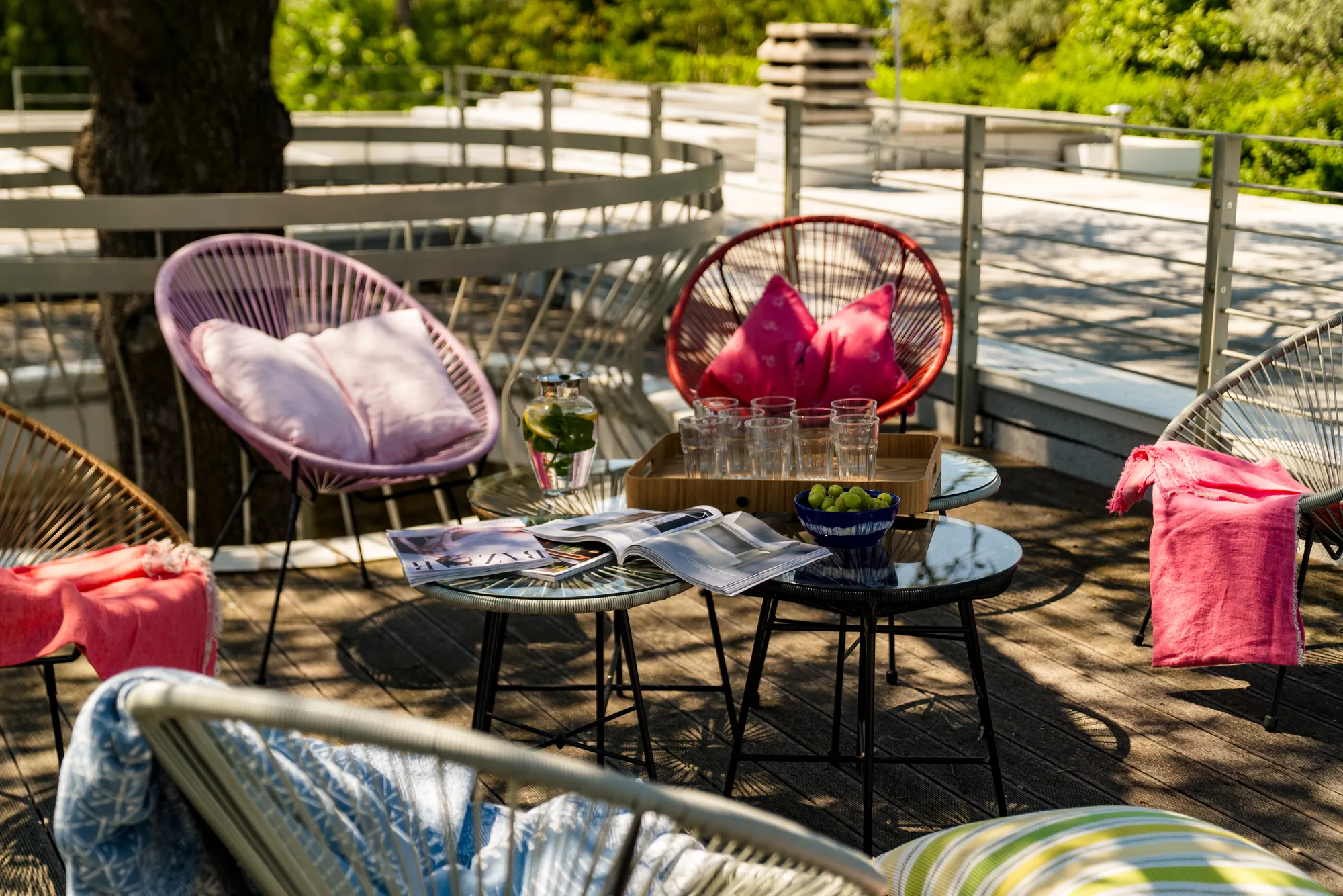 Pink and red Acapulco chairs with cushions and a coffee table on the roof terrace