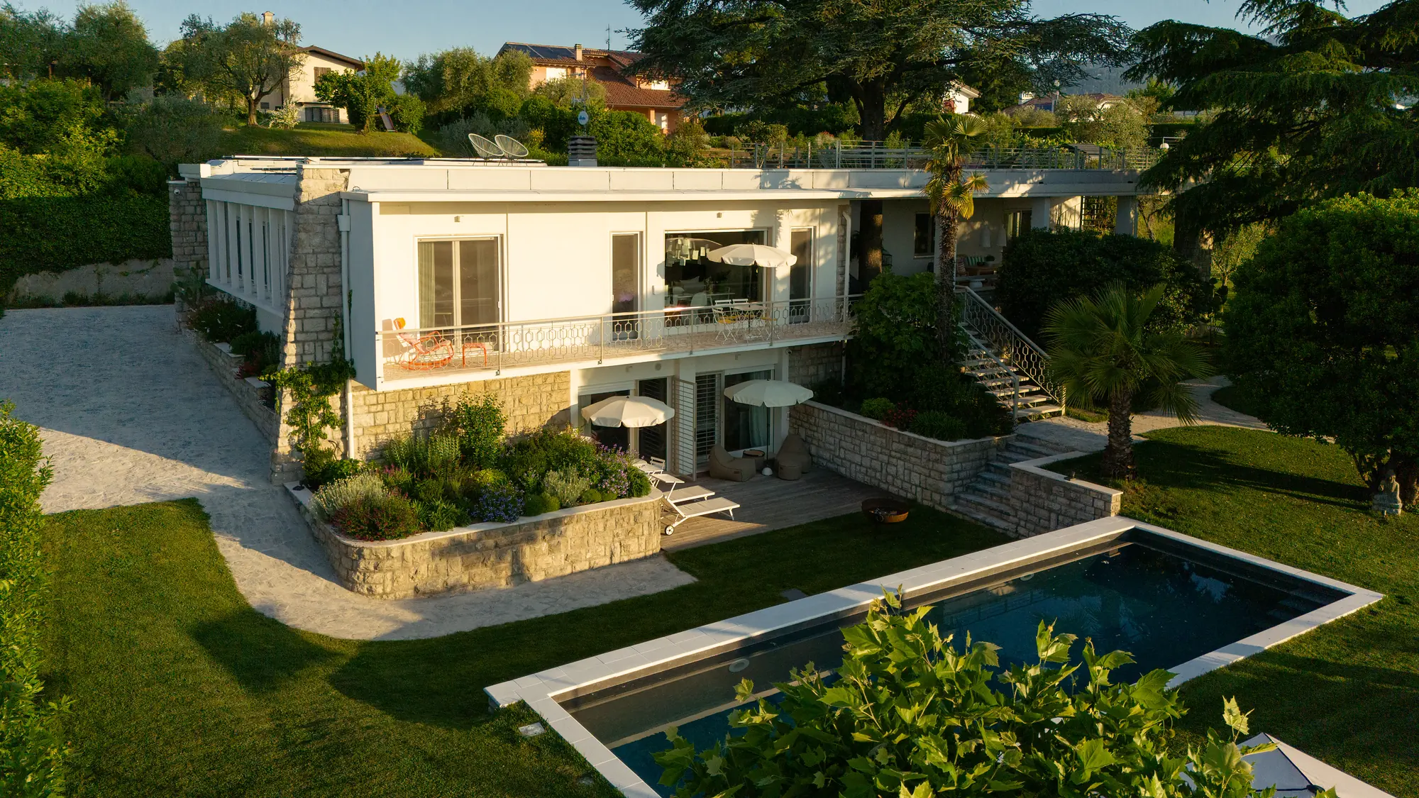 Aerial view of the flat-roofed modernist villa with its rectangular pool and lawn in San Felice del Benaco