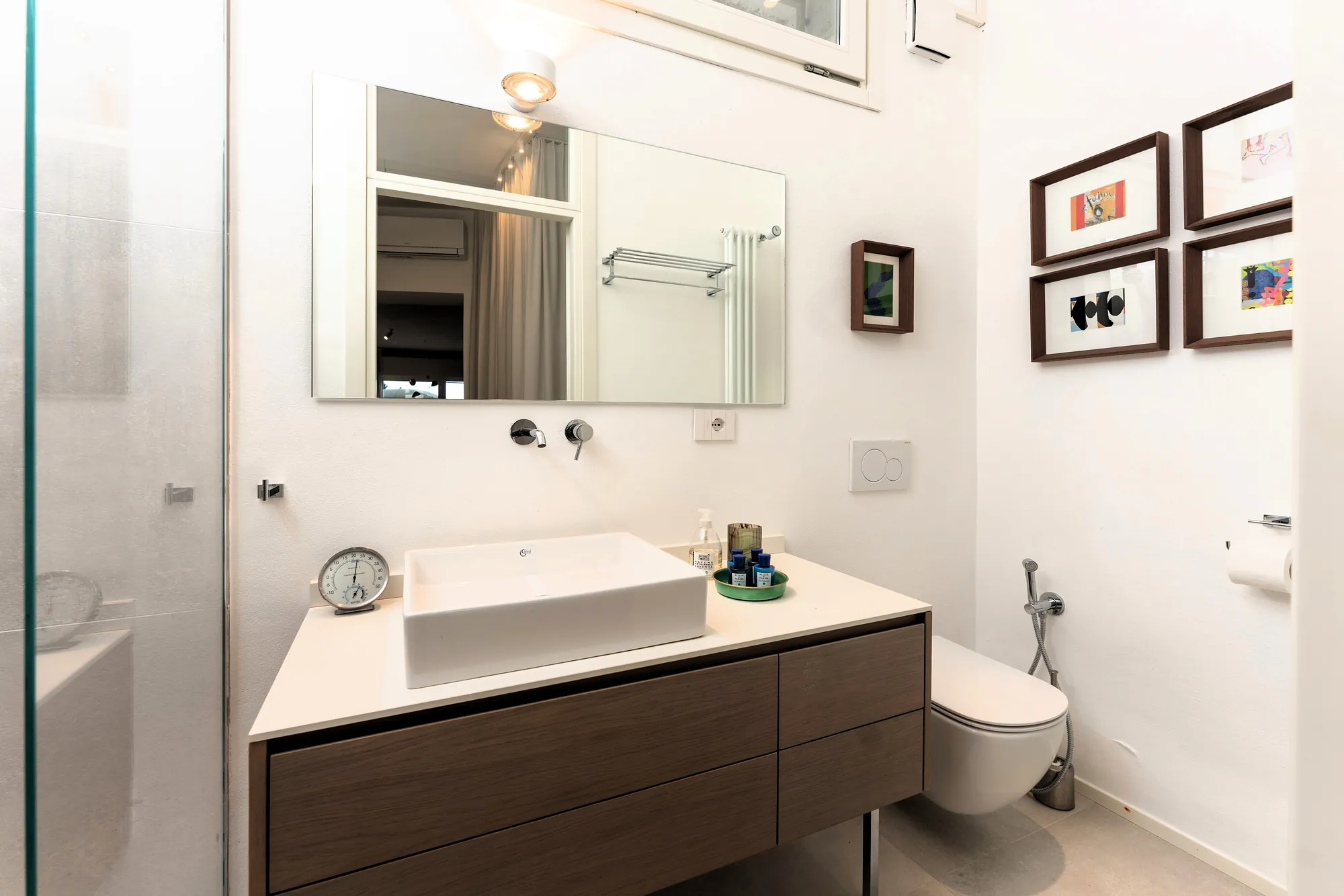 Designer bathroom with a white vessel basin, wooden vanity and framed art