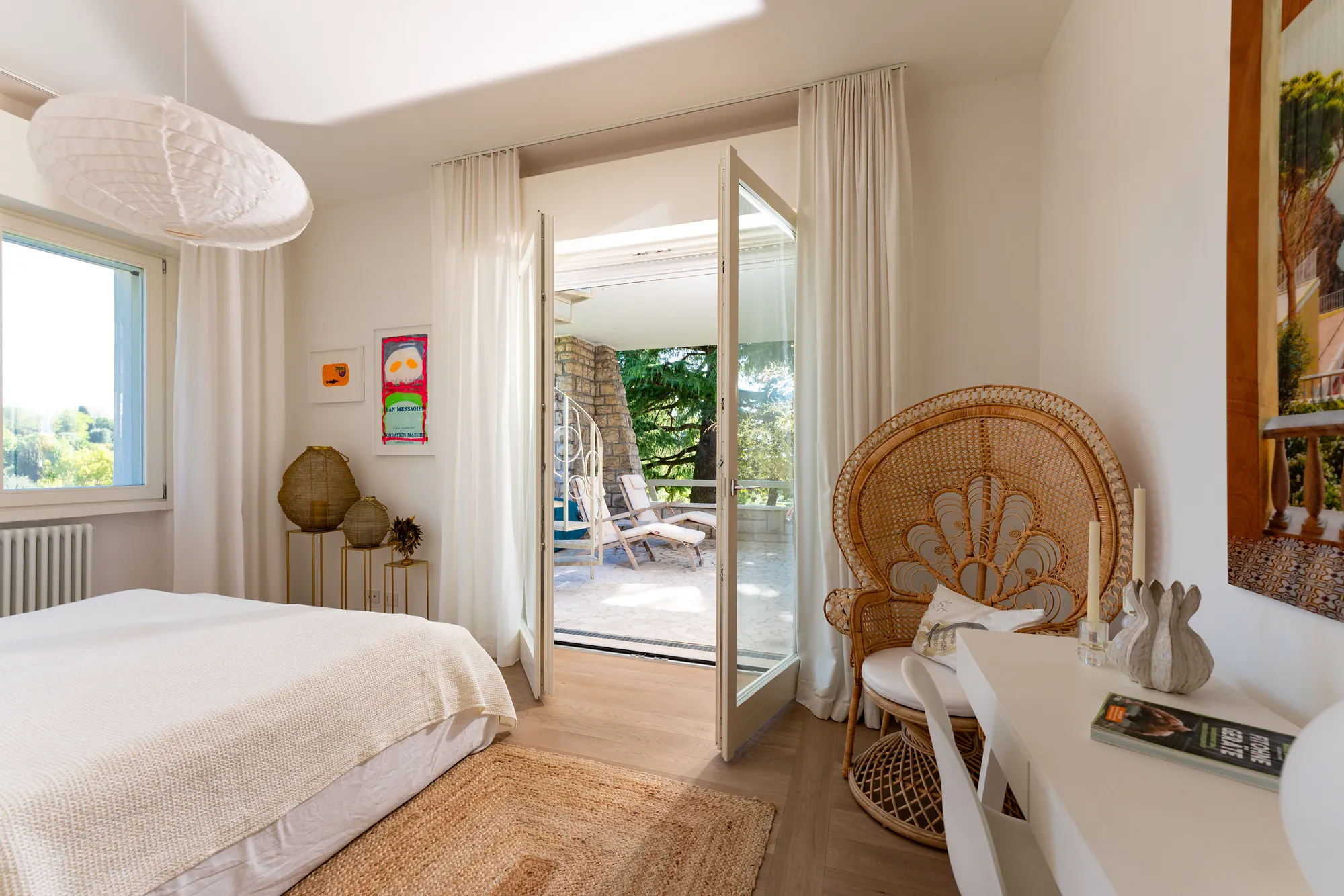 Bedroom with a rattan peacock chair and doors opening onto the terrace