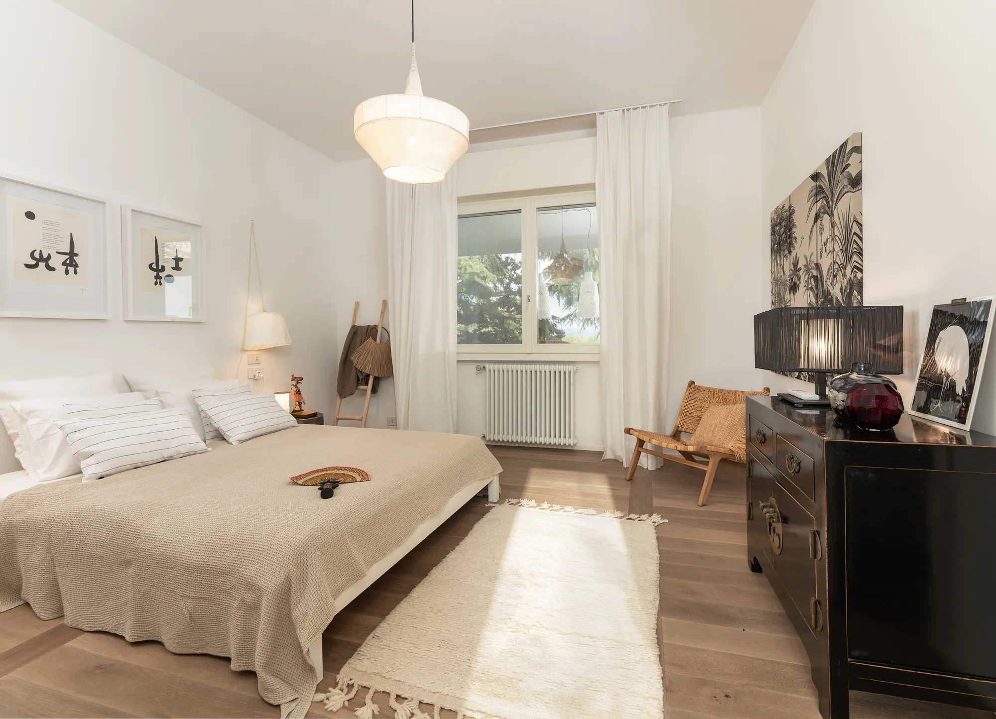 Double bedroom with oak parquet, a black chest and a window onto the garden