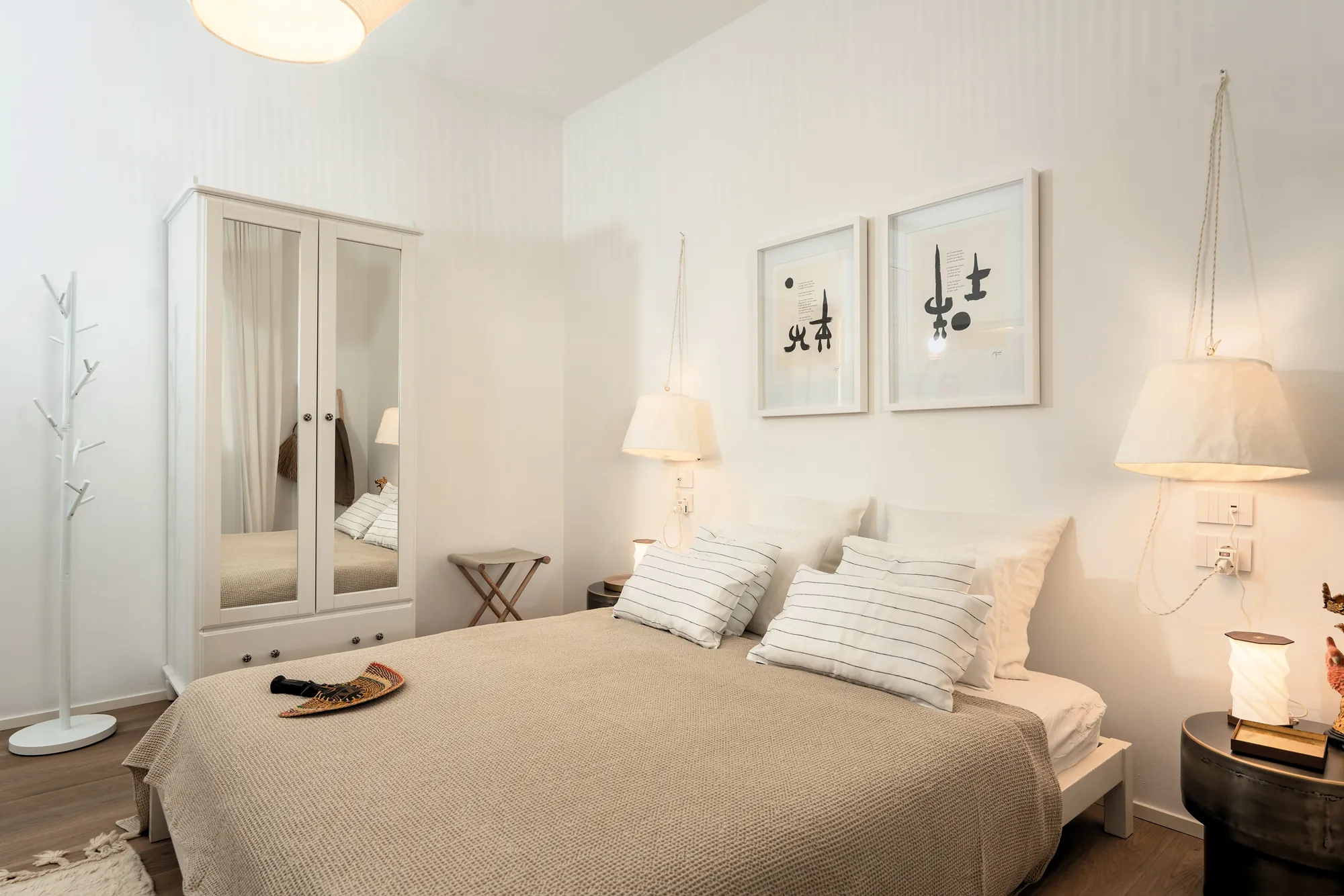 Double bedroom with mirrored wardrobe, bedside lamps and black-and-white graphic prints