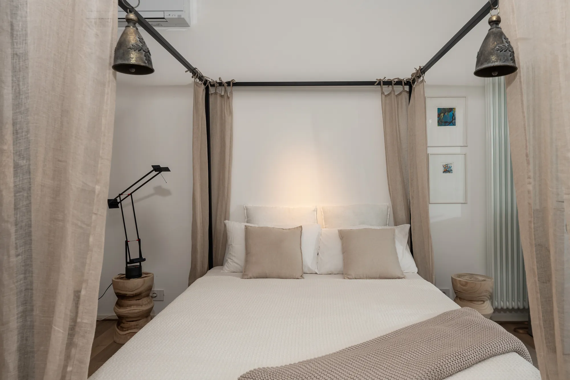 Four-poster bed with linen drapes, iron lanterns and soft natural tones