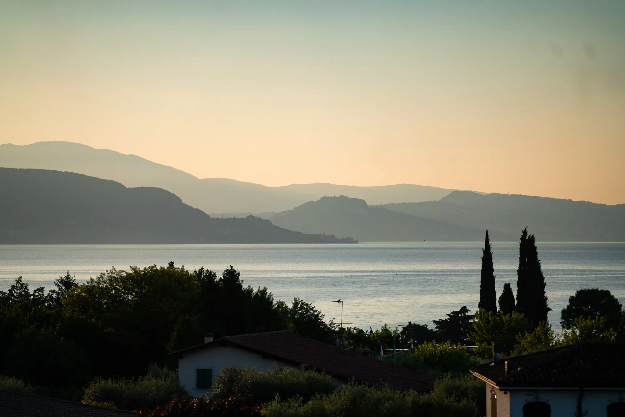 Panoramic sunset over Lake Garda and its mountains, seen from the villa's roof terrace