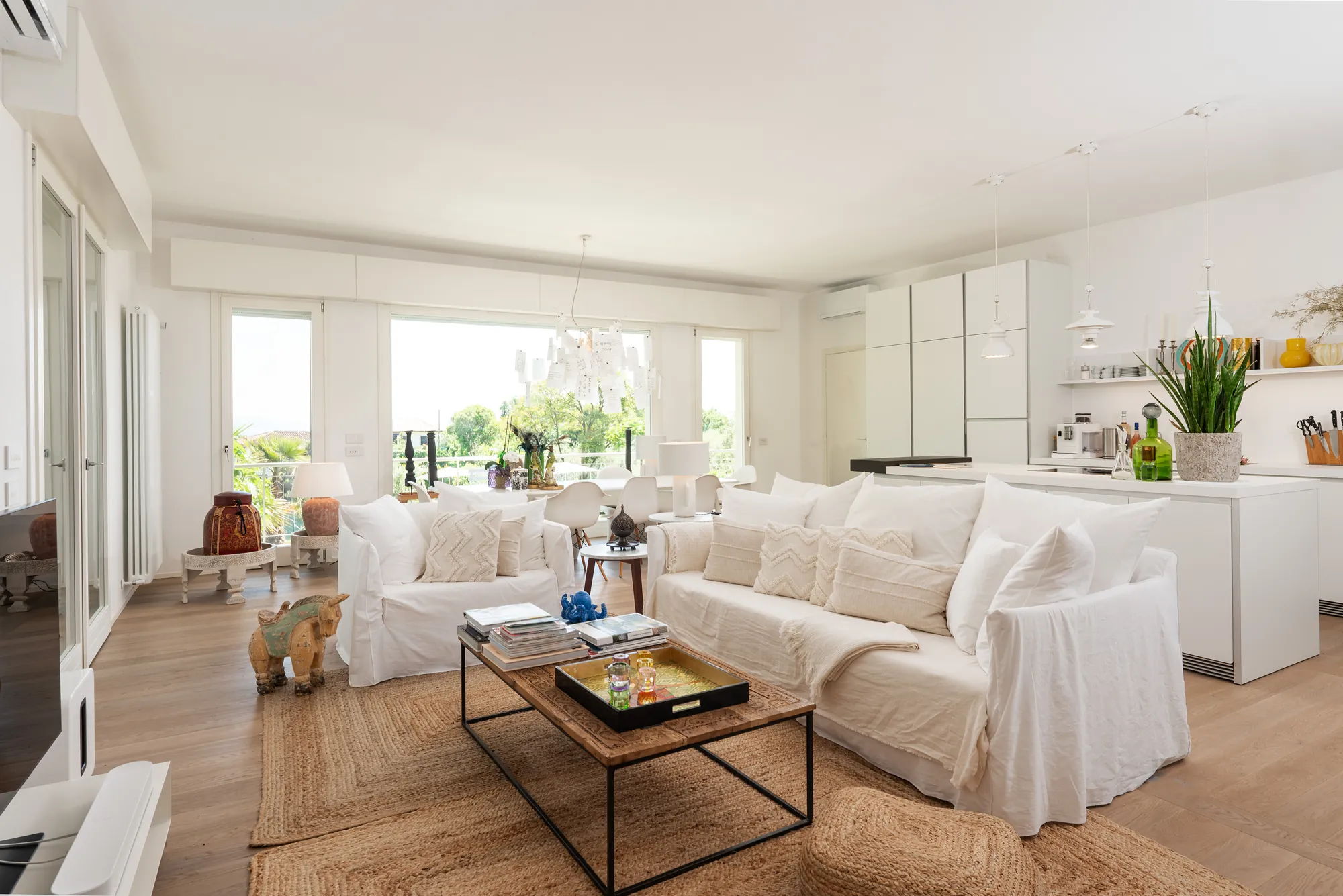 The light-filled 80 m² living area with white sofas, coffee table and open kitchen beyond
