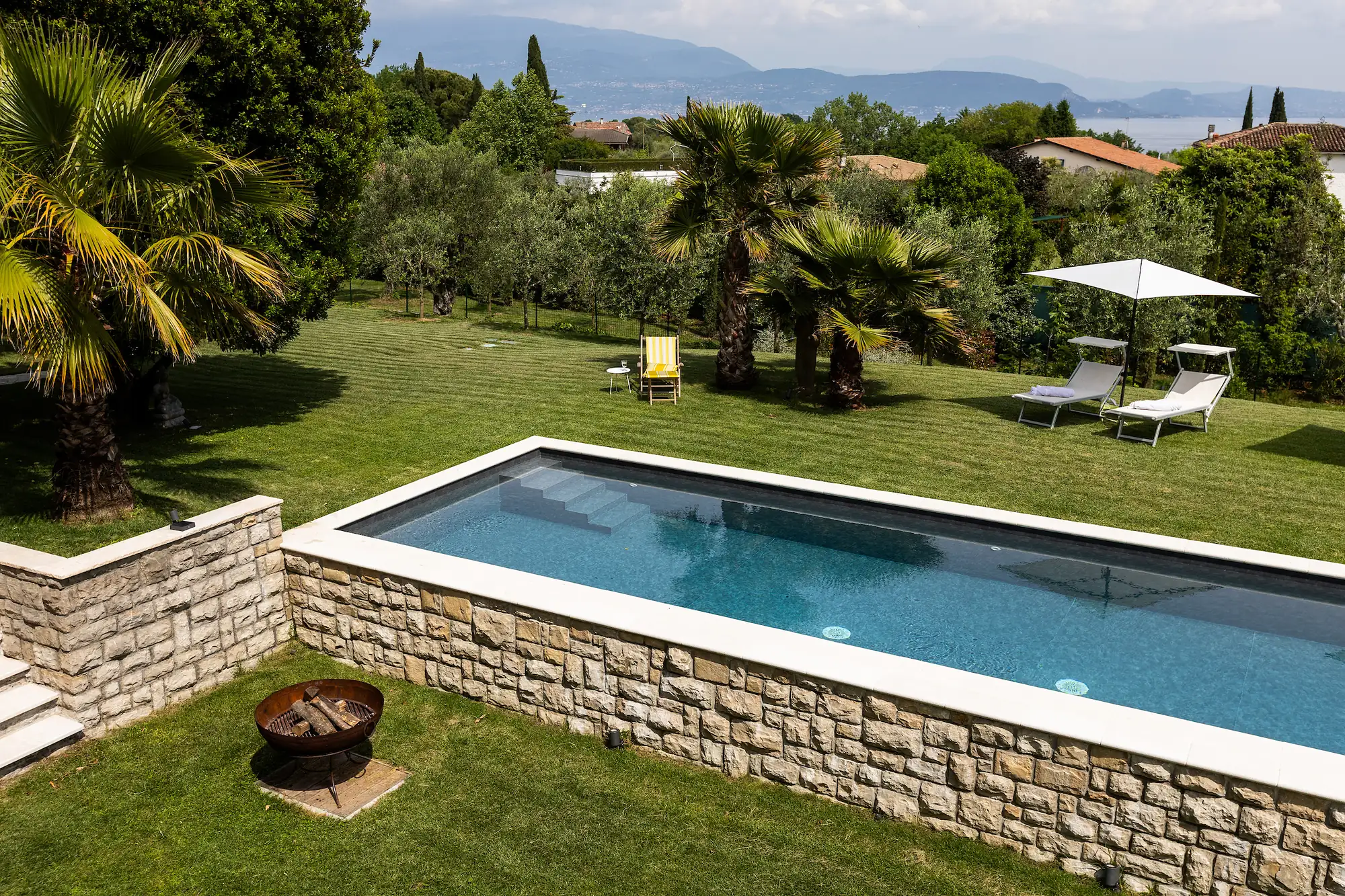 The raised pool with stone walls and a view toward Lake Garda