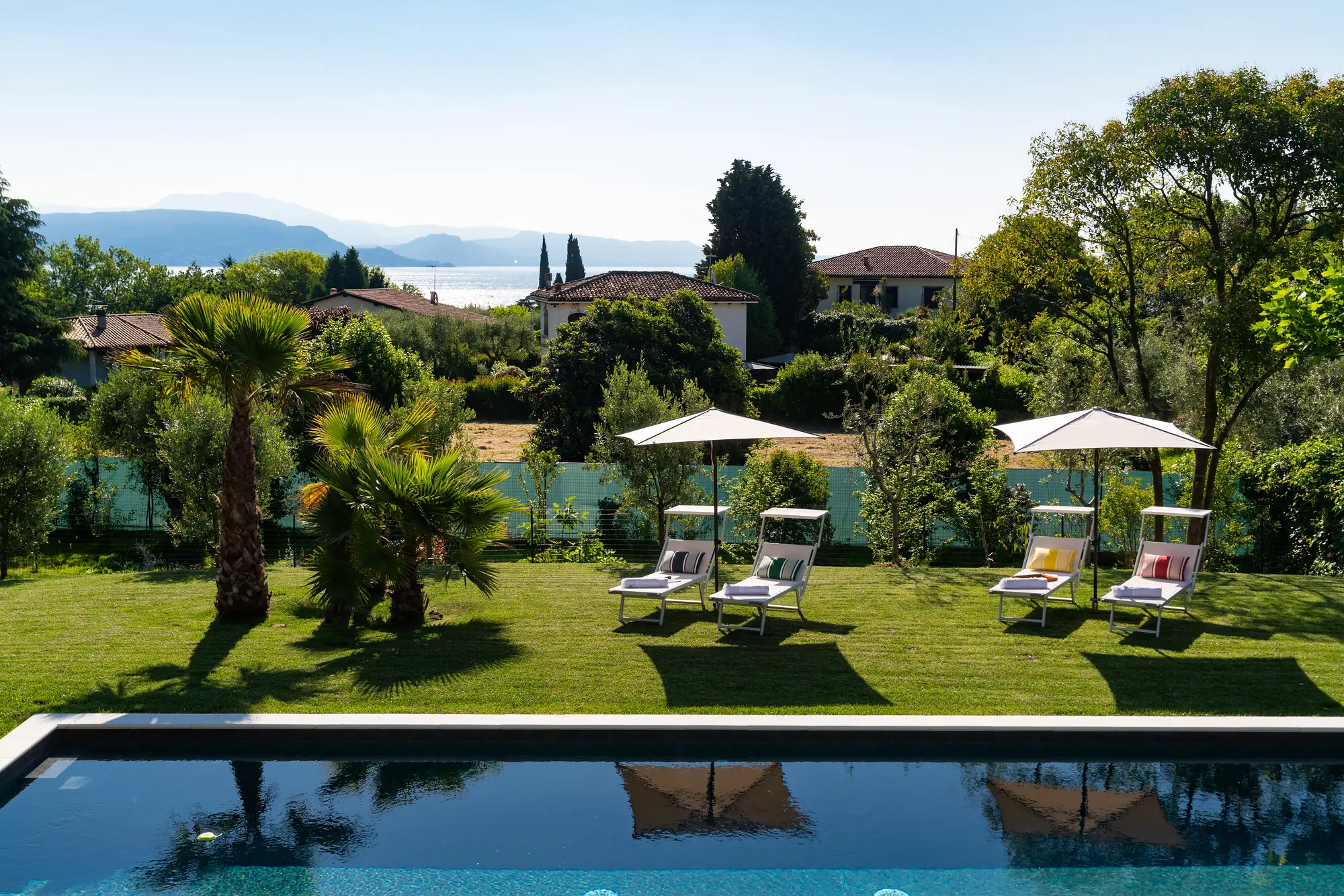 The pool and sun loungers with Lake Garda shimmering beyond the trees