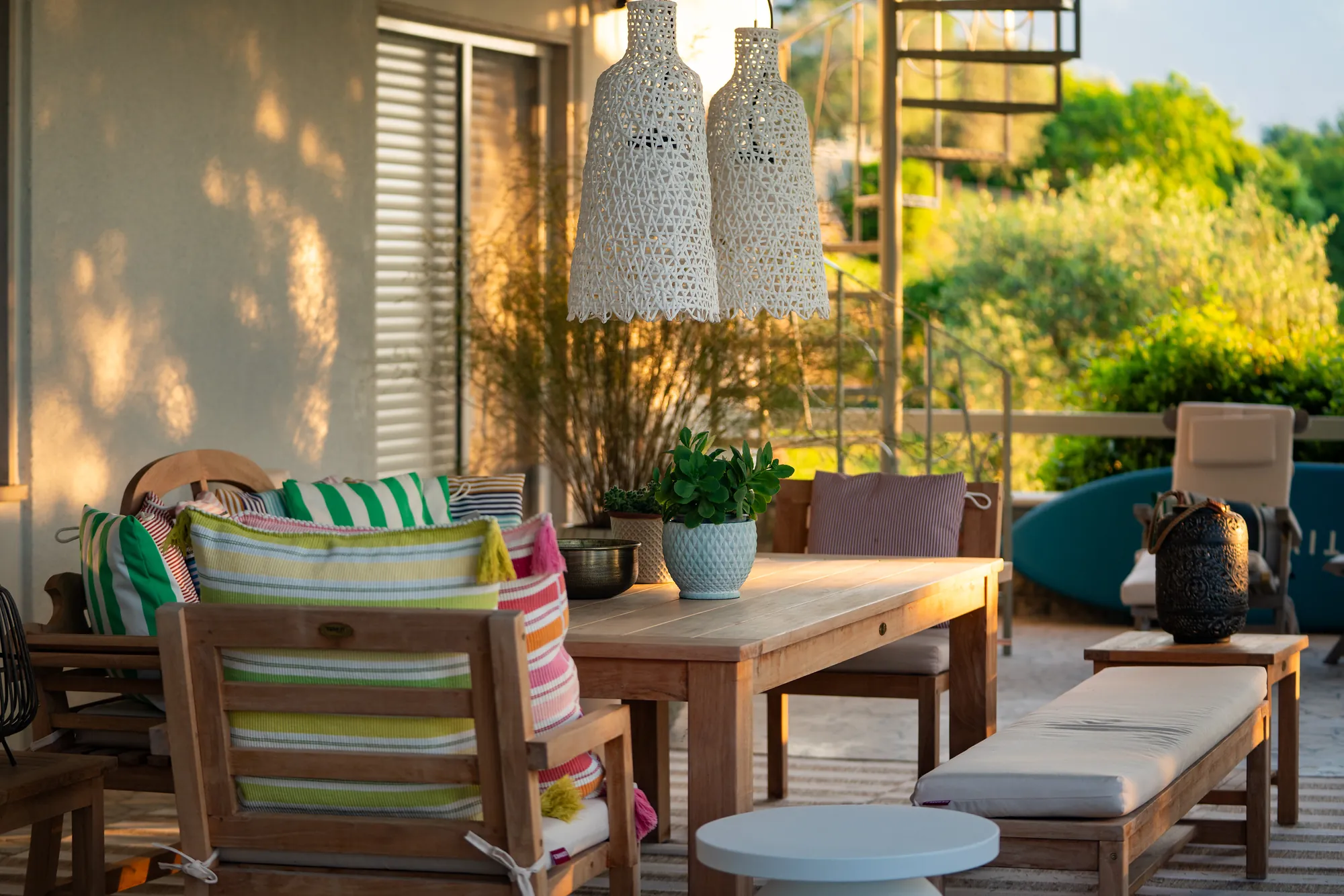 The terrace lounge in warm golden-hour light with cushions and woven lamps