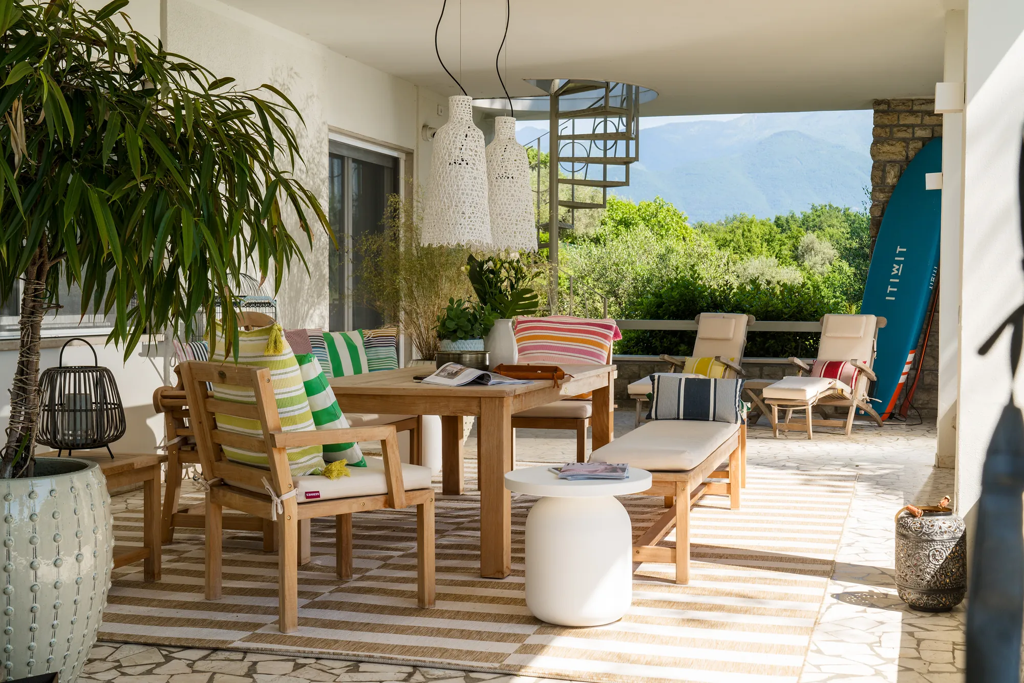 Teak lounge chairs on the terrace with a spiral staircase and views of the mountains