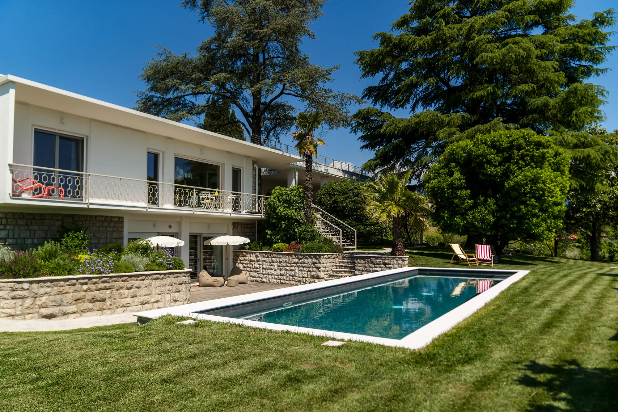 The villa's 11-metre saltwater pool and striped lawn in front of the house on a summer day