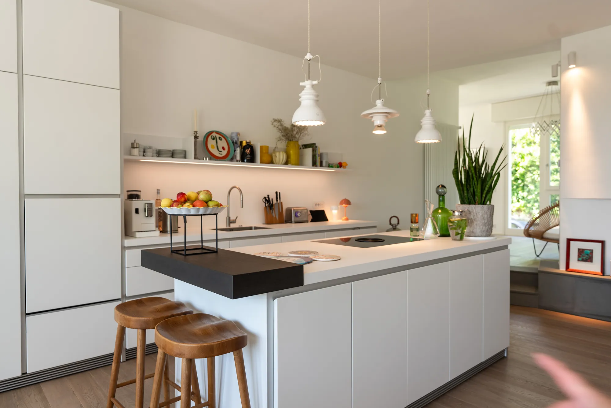 The white Bulthaup kitchen with island, wooden bar stools and Miele appliances